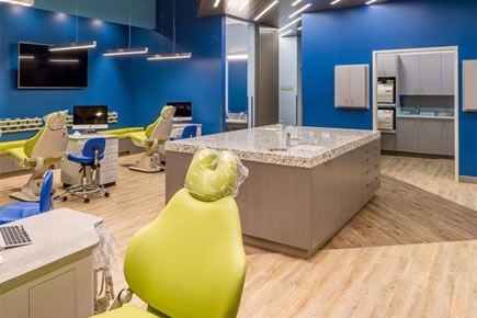 Modern orthodontic office reception area with blue walls, dental chairs, and contemporary furniture design.