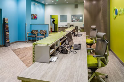 Modern orthodontic office reception area with colorful walls, desk, and comfortable seating spaces.