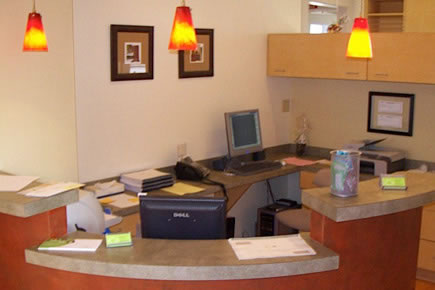 Modern orthodontic office reception desk with computer, warm lighting, and professional decor.