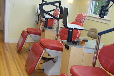 Modern orthodontic office interior with red dental chairs and equipment arranged in treatment room.