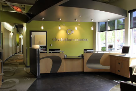 Modern orthodontic office reception area with green walls and contemporary desk design.