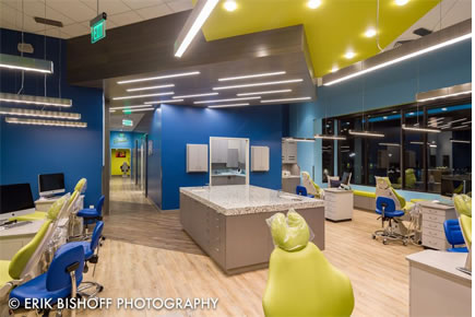 Modern orthodontic office reception area with blue walls, yellow accents, and contemporary furniture design.