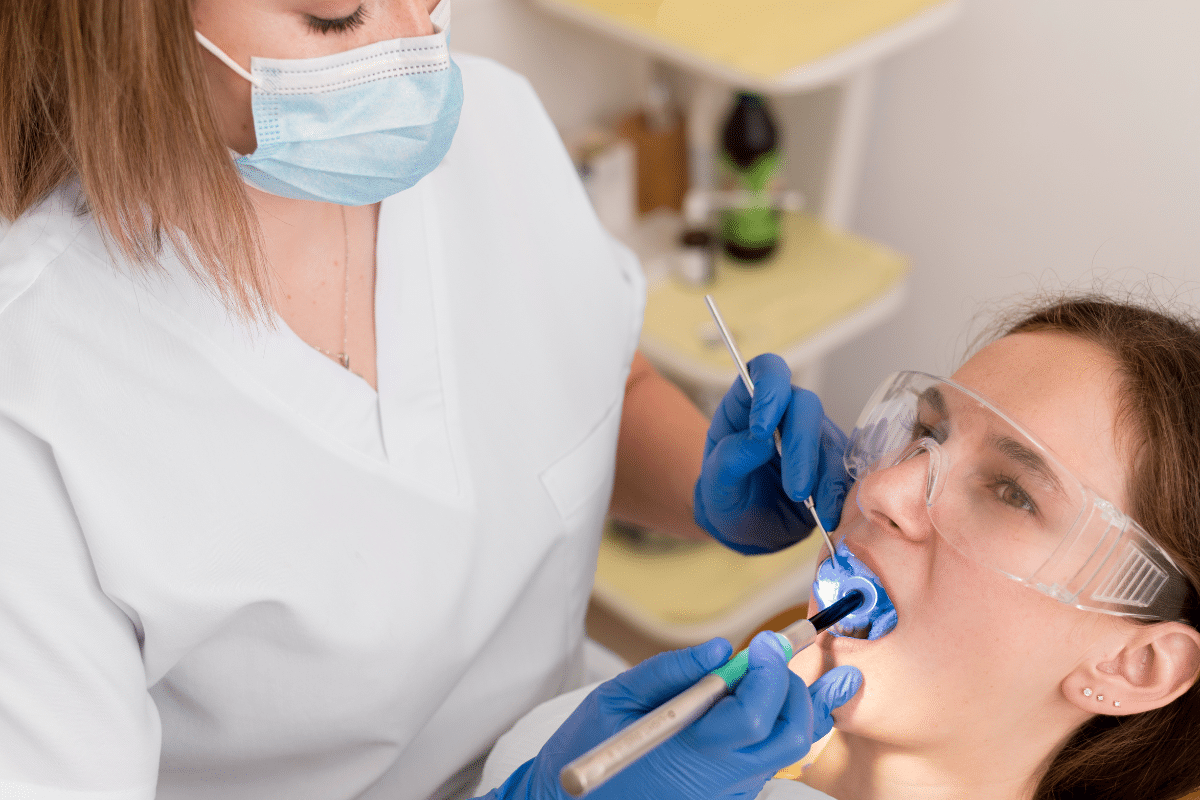 Orthodontist in mask and gloves examining patient's teeth during dental appointment