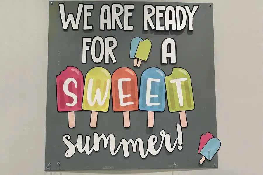 Colorful sign reading "We are ready for a sweet summer" with popsicle illustrations on gray background.
